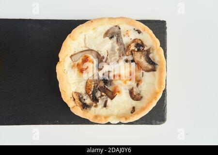 Tart with mushrooms and cheese on a white plate Stock Photo