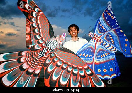 A young man offers butterfly kites on a beach on the island of Bali Stock Photo