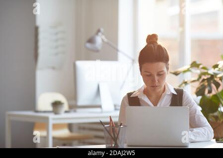 Serious businesswoman concentrating on her online work using laptop working at her workplace at office Stock Photo