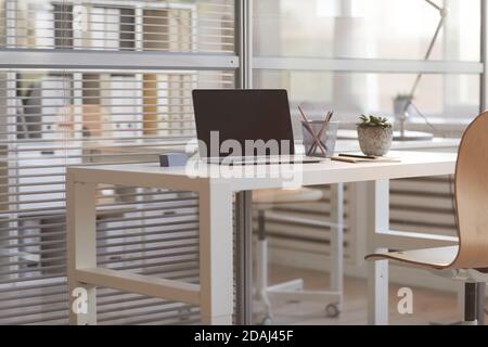 Image of laptop with blank screen on the table at empty office interior Stock Photo