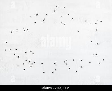 Christmas confetti frame. Flat lay of black and silver confetti on a white background. Top view. Copy space Stock Photo