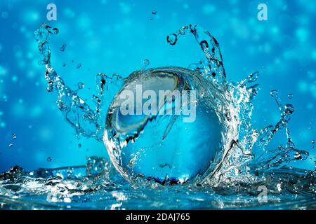 water wave splashing on a transparent ball in a blue background Stock Photo