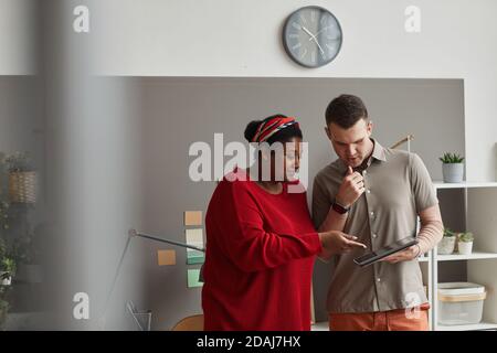 Business partners watching online presentation on digital tablet and discussing it at office Stock Photo