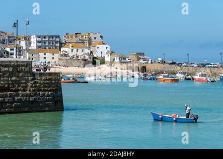 Man on small boat in St Ives harbour at high tide, Cornwall, UK Stock Photo