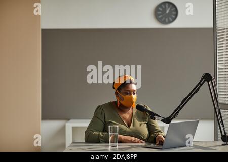 Radio host typing on laptop and speaking on microphone on the radio Stock Photo