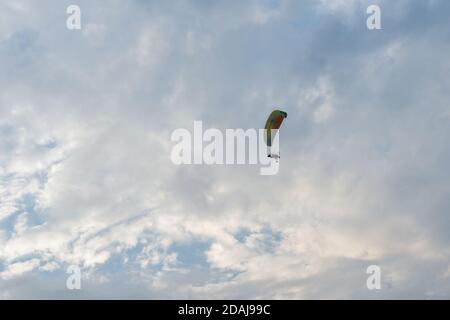 Tandem motor paraglider flies through a beautiful evening cloudy sky with two people. Stock Photo