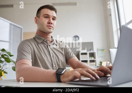 Computer programmer sitting at the table and typing on laptop computer at office Stock Photo