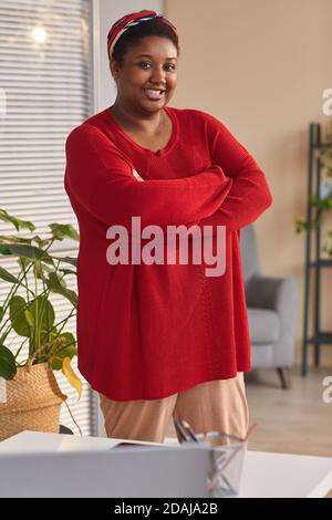 Portrait of African overweight woman in casual clothing standing with arms crossed and smiling at camera Stock Photo