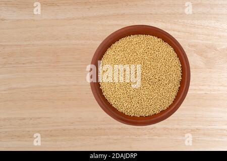 Top view of amaranth seeds in a small bowl on a wood tabletop. Stock Photo