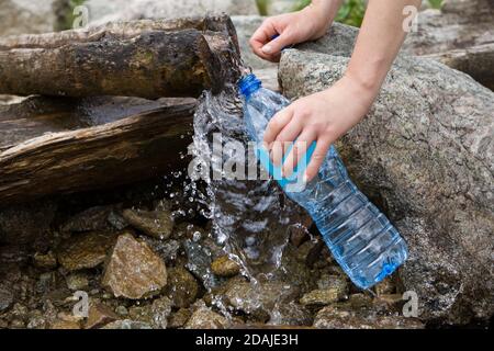 Plastic bottle water filling, natural pure water source. Taking spring water from a mountain spring. Stock Photo