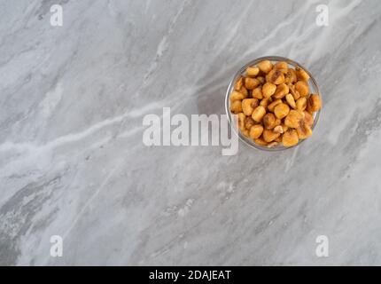 Organic corn nuts in a glass bowl offset on a gray countertop illuminated with natural light. Stock Photo