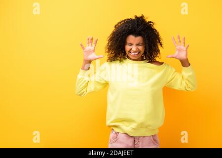 angry african american woman in sweatshirt on yellow Stock Photo