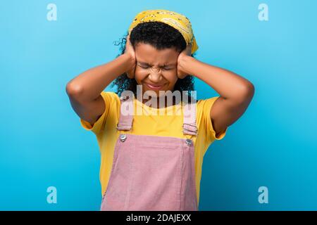 african american woman suffering from pain while having migraine on blue Stock Photo