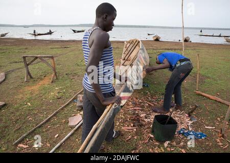 Selingue area, Mali, 27th April 2015; Boat builder and repairer, Ke Karonta, 17 (blue shirt) has never been to school.  His father is a boat builder and he is following in his father's footsteps. Stock Photo