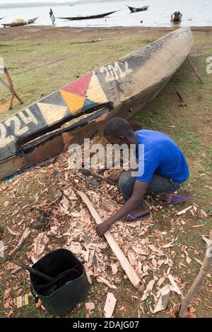 Selingue area, Mali, 27th April 2015; Boat builder and repairer, Ke Karonta, 17 (blue shirt) has never been to school.  His father is a boat builder and he is following in his father's footsteps. Stock Photo