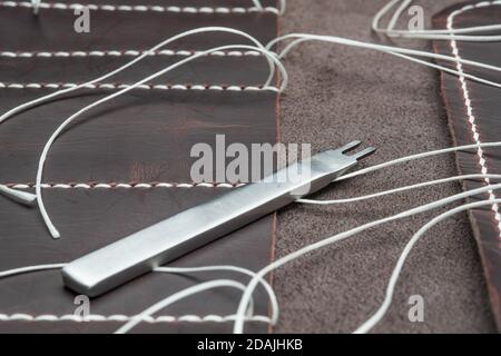 punch for leather products lying on a material with white threads Stock Photo
