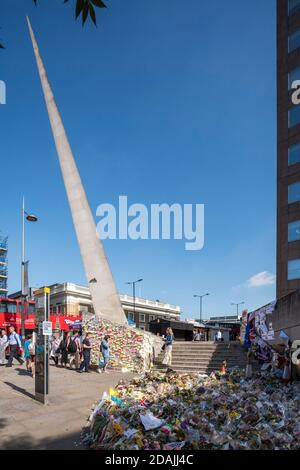 View looking north west with floral tributes and post-it notes stuck to the base of the needle as tributes to the terror attack victims of June 2017. Stock Photo