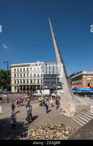 View looking west with floral tributes and post-it notes stuck to the base of the needle as tributes to the terror attack victims of June 2017. Southw Stock Photo