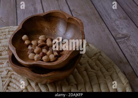 Closeup shot of hazelnuts in a wooden bowl on a cork trivet Stock Photo
