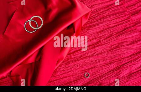Red background and metal rings. Two textures of fabric. Satin and crinkled taffeta. Stock Photo