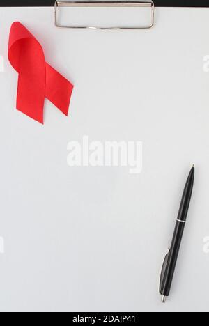 The red ribbon and black pen on empty sheet of paper Stock Photo