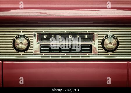 Retro styled image of an old car radio inside a red classic car Stock Photo
