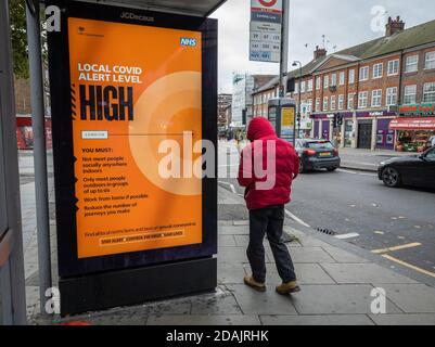 A local Covid-19 alert level sign by a bus stop on a London high street. Stock Photo