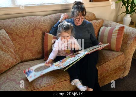 Grandmother reading to grandchild Britain Uk Stock Photo