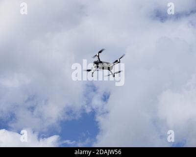 a drone flying in a blue sky with clouds Stock Photo