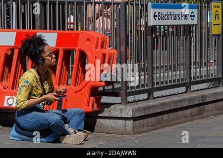 LONDON, GREAT BRITAIN, April 22, 2018 : Young woman listening to music while waiting in Blackfriars district, on the London Marathon day. Stock Photo