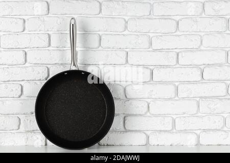 Frying pan against white brick wall front view Stock Photo