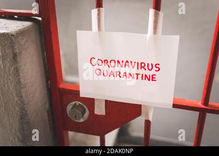 Sheet of Paper Saying Coronavirus Quarantine in Red Letters Taped on the Locked Iron Door Stock Photo