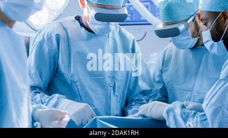 Surgeons Wearing Augmented Reality Glasses to Perform State of the Art Surgery in Technologically Advanced Hospital. Doctors and Assistants Working Stock Photo