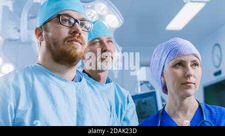 Diverse Team of Professional surgeon,  Assistants and Nurses Standing Proudly in the Real Modern Hospital with Authentic Equipment.  Stock Photo