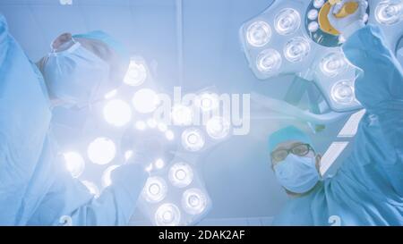 Two Professional Surgeons Use Digital Tablet Computer while Standing in the Modern Hospital Operating Room. Stock Photo