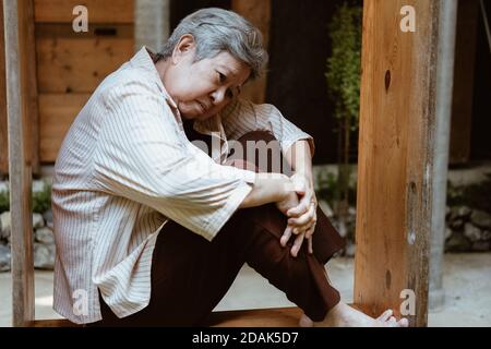 stressed depressed fatigued sad upset asian old asian elderly senior elder woman sitting at home Stock Photo