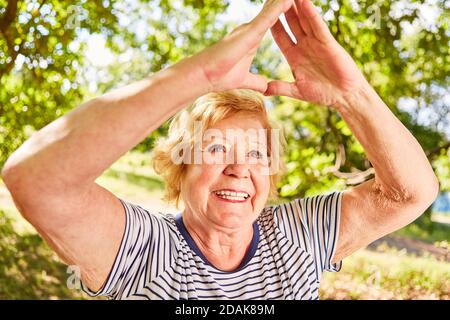 Smiling elderly woman doing a yoga exercise for health and relaxation in nature Stock Photo