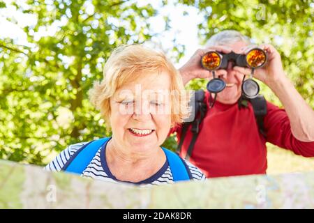 Couple of seniors as ornithologists on a hike with a map and binoculars Stock Photo