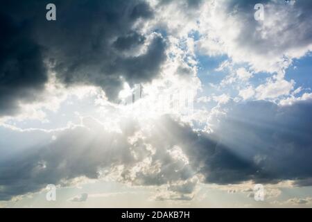 Beautiful dramatic sky with sun rays shining through dark clouds for background Stock Photo