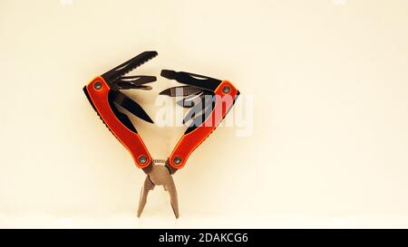 Pliers, multifunctional with functional tools, for use at home, in orange color with white background, copy space, side view, selective focus Stock Photo