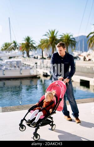 Man is trying to catch a falling pink stroller with his daughter sitting inside it Stock Photo