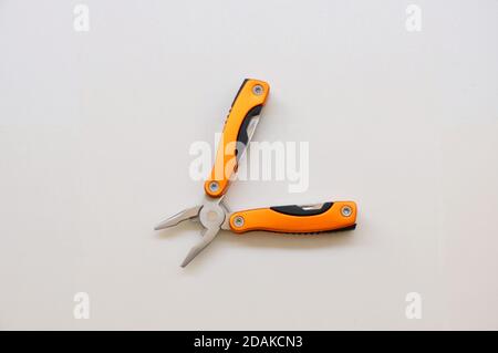 Pliers. Multifunctional pliers with functional tools, for use at home, in orange color with white background, copy space and top view Stock Photo