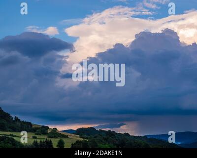 Massive storm clouds in the sky over hilly landscape Stock Photo