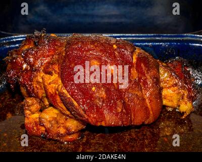 Roasted pork knuckle in a roasting pan with lots of baked fatty juice Stock Photo