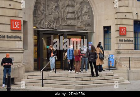 Students wearing protective face masks stand outside the LSE Old Building at London School Of Economics. While most shops and businesses had to close during the second national lockdown in England, universities and schools are permitted to stay open. Stock Photo