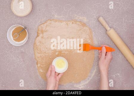 A step-by-step recipe for sweet cinnamon rolls. Step 3- butter the dough Stock Photo