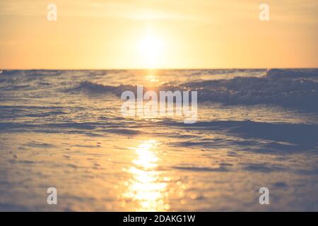 close up of a sea waves with sunjust above the horizon during nostalgy sunset Stock Photo