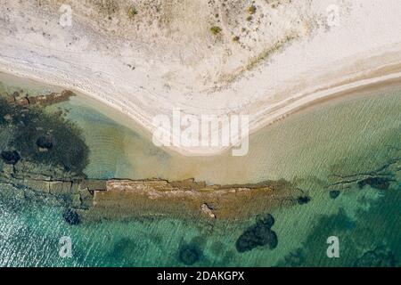 Calm shallow sea and land background aerial drone view.  Clear turquoise crystal water caress the sandy empty beach. Birds eye view of rocky sea botto Stock Photo