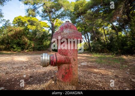 Fire protection concept. Firefighting public system, fire hydrant rusty metal red color outdoors in nature background. Old extinguisher with plug mean Stock Photo