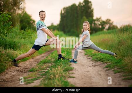 Athletic young father and little daughter do exercises in stadium. Healthy lifestyle Stock Photo